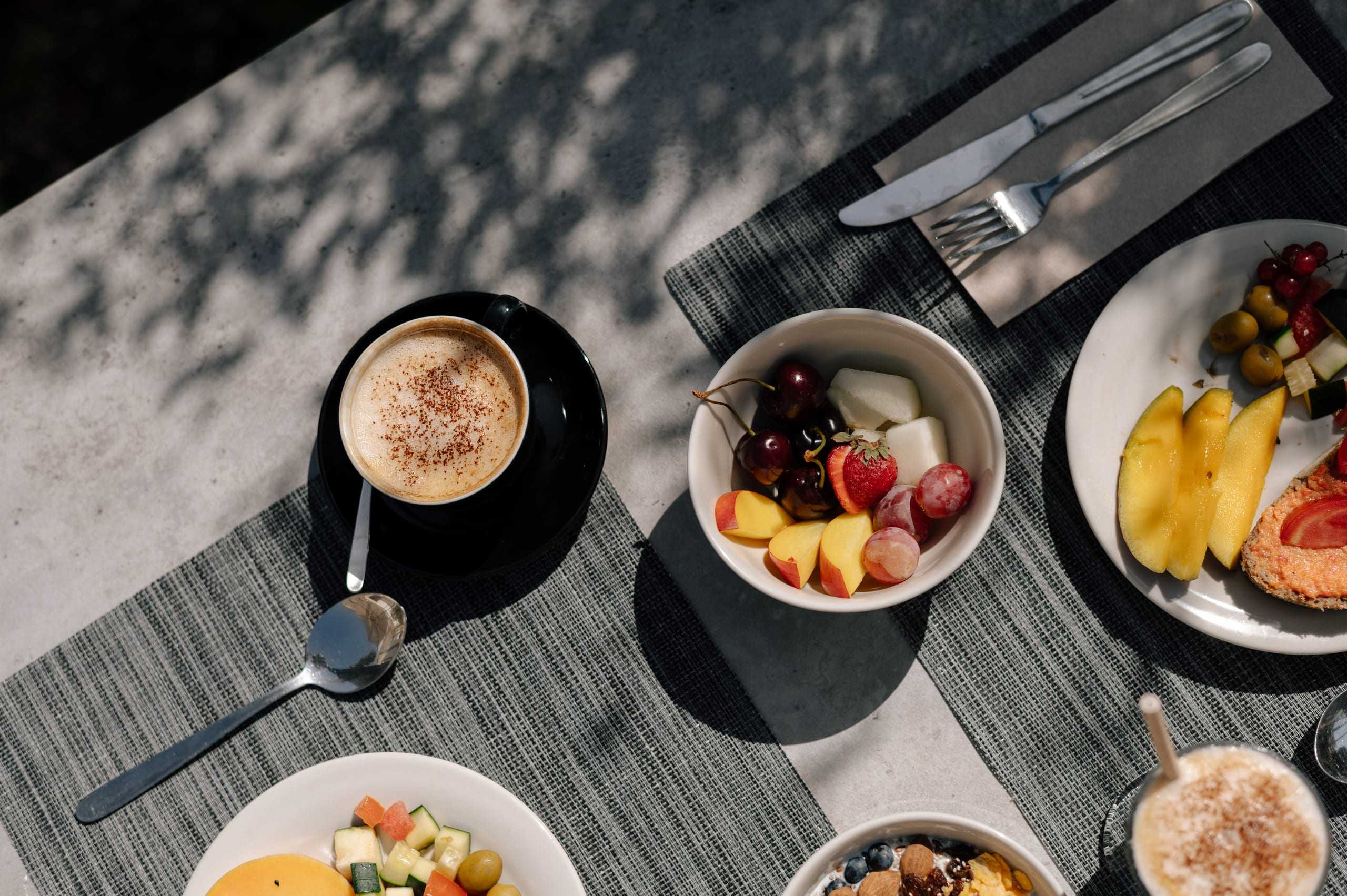 Breakfast table in the sun: coffee, fruit and bowls